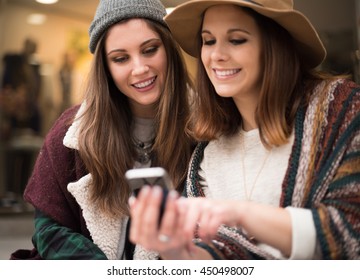 Trendy young women using smartphone in the city