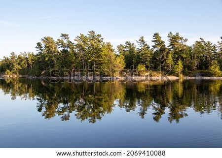 tress reflecting in the water along the rocky shore of Georgian Bay