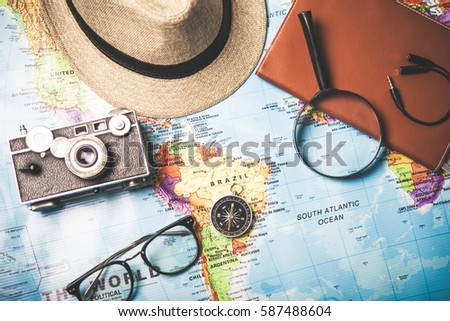 Treveling concept. Hat,Vintage camera with compsss and eye glasses on world map background.