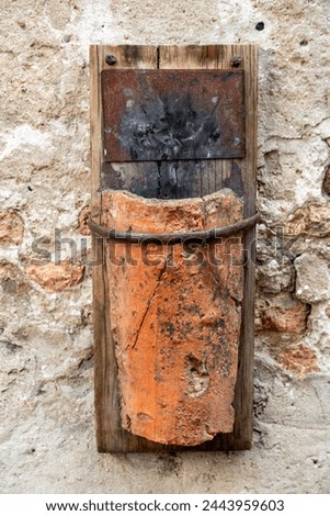 Treviso, Venetien - Italy - 06-08-2021: Rustic terracotta lamp mounted on a weathered wall, blending art and history