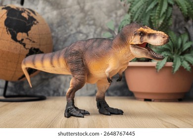 T-rex Dinosaur toy. Tyrannosaurus rex with Dorstenia Plant in plastic pot simulate and mini globe for the atmosphere of the ancient era on wooden table. - Powered by Shutterstock - Get 15% off with code: PIKWIZARD15