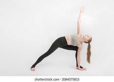 Triangle Pose. Trikonasana. Sports girl does yoga and performs asanas on white background. Gymnastics, stretching
