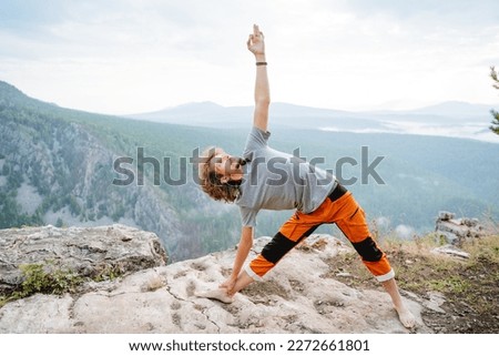 Triangle pose in yoga guy pulls his hand up, man performs asana on body balance, meditation in the mountains, mental fortitude, body flexibility. High quality photo