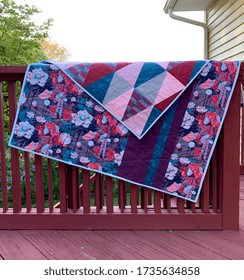 Triangle Quilt With Floral Back In Blues And Pinks. Handmade Heirloom Displayed On A Fence.