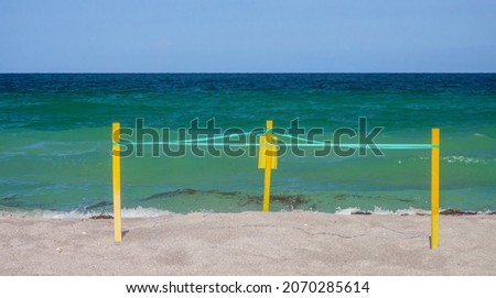 Triangular area demarcated with signposts and ribbon to protect sea turtle nest on sandy beach of barrier island along the Gulf Coast of Florida
