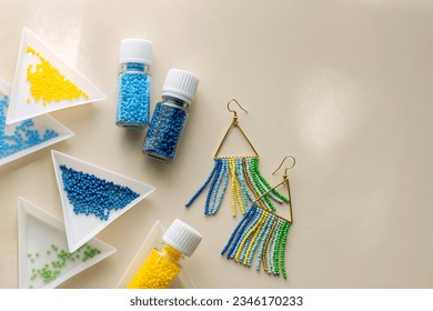 Triangular bead trays with beaded earrings. Different colored seed beads in containers for needlework and beading. Creativity and  hobby concept