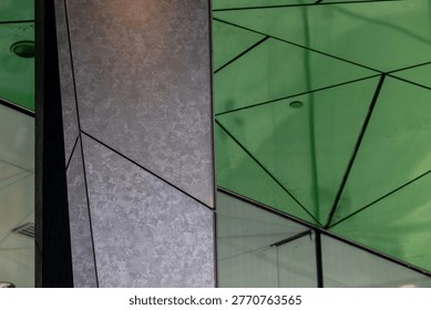 Triangular building details with green ceiling and black granite angular columns 