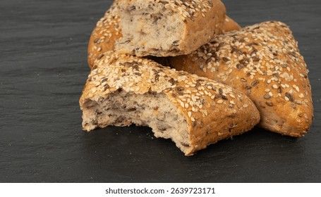 Triangular bun closeup. Wheat bread with sesame and flax seeds, healthy whole grain bakery on black background