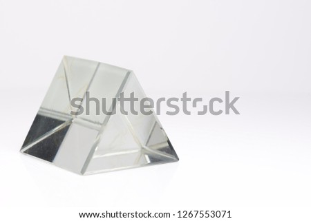 Triangular, clear glass prism isolated on a white background.