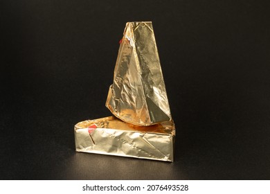 Triangular cream cheeses wrapped in foil on a black background. Portioned triangular cheeses. - Shutterstock ID 2076493528