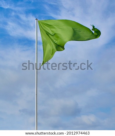 A triangular green flag over a cloudy sky.