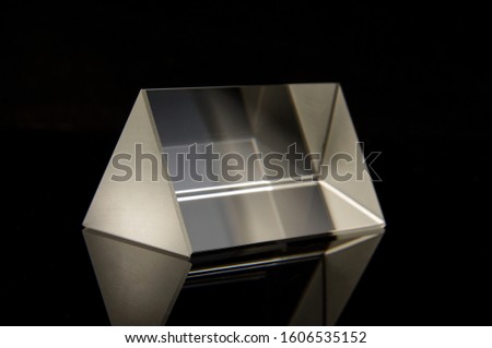 Triangular optical prism for scientific experiments isolated on the black reflective background