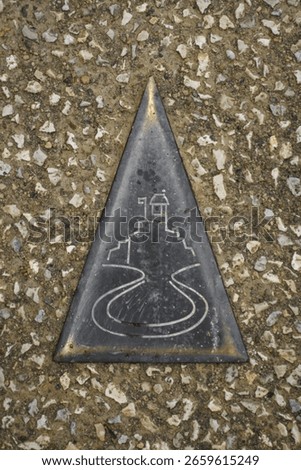 Triangular pavement plaque depicting Besançon’s Vauban citadel and looping Doubs river; concept: heritage trail, wayfinding, UNESCO fortress city.