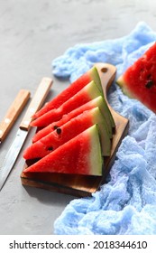 Triangular pieces of ripe watermelon on a wooden cutting board. Vertical photo. Selective focus