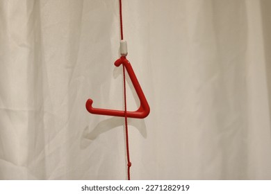 Triangular red emergency pull cord against neutral background with copy space