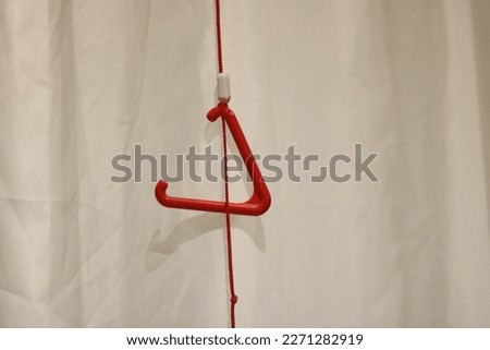 Triangular red emergency pull cord against neutral background with copy space