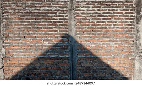 The triangular shadow of the house on the brick wall