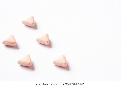 Triangular shape vitamin tablets on white background