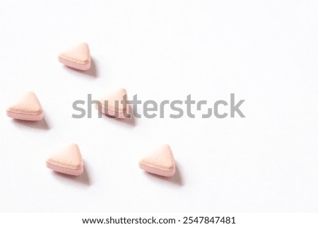 Triangular shape vitamin tablets on white background