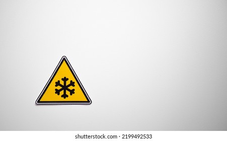 A triangular sign with a snowflake on a white isolate. Danger of freezing. A cold temperature sign on a white background. Precipitation in the form of snow emblem.