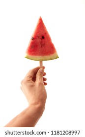 A triangular slice of a watermelon on a stick to hold a male hand on a white background with copy space. Conception of berry ice cream