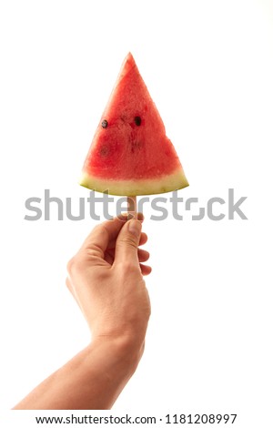 A triangular slice of a watermelon on a stick to hold a male hand on a white background with copy space. Conception of berry ice cream