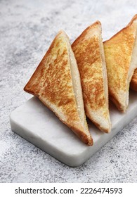 Triangular slices of toast bread on a white marble cutting board