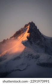 Triangular snow covered mountain with red sun light