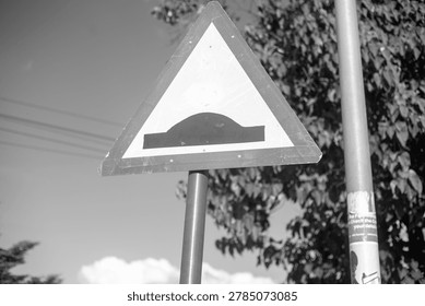 Triangular speed hump warning road sign.