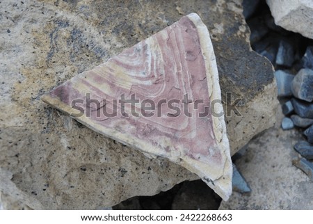 Triangular stone with red and white layers, striation, stripes. Red orange and white rock close up isolated macro