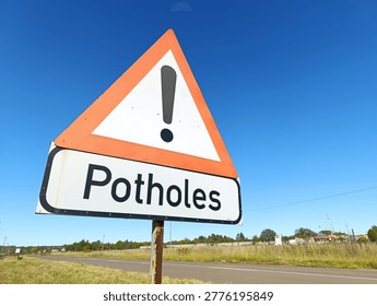 A triangular warning sign alerts motorists to dangerous potholes on an unmaintained road in South Africa.