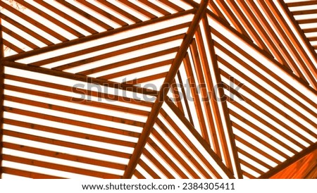 Triangular wooden crossbars in brown and orange. Wooden crossbars connecting to each other form different shapes - triangle, rectangle. Many parallel lines. Figured object. Urban park architecture