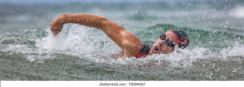 Triathlete Man Swimming Freestyle Crawl In Ocean Panorama Banner. Male Triathlon Swimmer Swimming In Professional Triathlon Suit Training For Ironman On Hawaii.