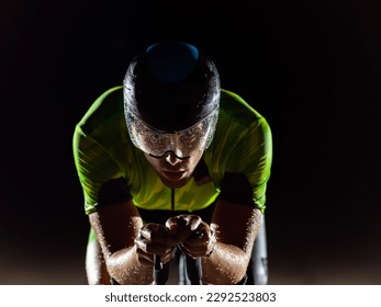 A triathlete rides his bike in the darkness of night, pushing himself to prepare for a marathon. The contrast between the darkness and the light of his bike creates a sense of drama and highlights the - Shutterstock ID 2292523803