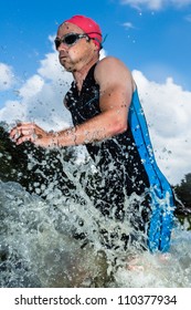 A triathlete is running out of the water