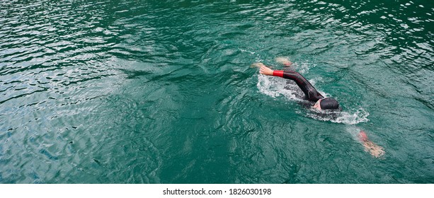 Triathlon Athlete Swimming On Lake Wearing Wetsuit