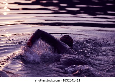 triathlon athlete swimming on lake in sunrise wearing wetsuit - Shutterstock ID 1832341411