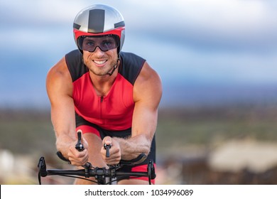 Triathlon Biking Man Cyclist Portrait Riding Bike. Male Triathlete Cycling On Triathlon Bike. Fit Man Professional Athlete On Triathlon Bicycle Wearing Time Trial Helmet For Ironman Race.