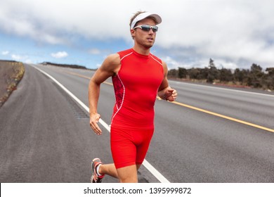 Triathlon Runner Man Triathlete In Tri Running Suit On Road During Kona Hawaii Competition Race. Male Athlete Wearing Sunglasses And Cap Sport Outfit.