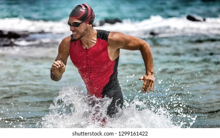 Triathlon swimming man running out of water during ironman race. Male triathlete finishing swim time competition. Fit athlete swimmer sprinting determined out of water in professional tri suit.