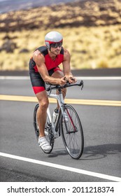 Triathlon Time Trial Cycling Triathlete Man Wearing Aero Bike Helmet With Visor Biking On Competition Race Day Riding Road Bicycle Vertical Shot.