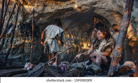 Tribe of Hunter-Gatherers Wearing Animal Skin Live in a Cave. Leader Brings Animal Prey from Hunting, Female Cooks Food on Bonfire, Girl Drawing on Wals Creating Art. Neanderthal Homo Sapiens Family