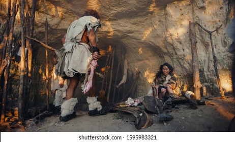 Tribe of Hunter-Gatherers Wearing Animal Skin Live in a Cave. Leader Brings Animal Prey from Hunting, Female Cooks Food on Bonfire, Girl Drawing on Wals Creating Art. Neanderthal Homo Sapiens Family