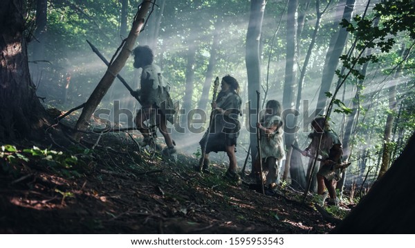 Tribe of Hunter-Gatherers Wearing Animal Skin\
Holding Stone Tipped Tools, Explore Prehistoric Forest in a Hunt\
for Animal Prey. Neanderthal Family Hunting in the Jungle or\
Migrating for Better Land