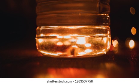 Trick Of The Light. Orange Light Background. Through The Bottle Of Water