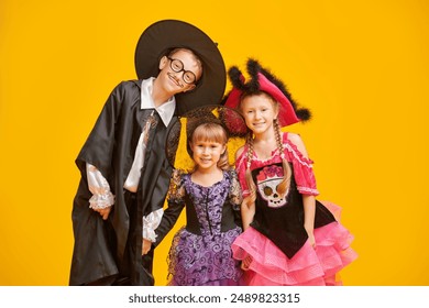 Trick or treating on Halloween. Three cheerful cute kids in Halloween costumes emotionally posing on a yellow background in the studio. - Powered by Shutterstock