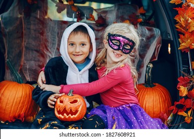 Trick Or Trunk. Children Celebrating Halloween In Trunk Of Car. Boy And Girl With Red Pumpkins Celebrating Traditional October Holiday Outdoor. Safe Alternative Celebration.