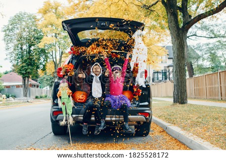 Trick or trunk. Children celebrating Halloween in trunk of car. Boy and girl with red pumpkins celebrating traditional October holiday outdoor. Social distance during coronavirus pandemic.