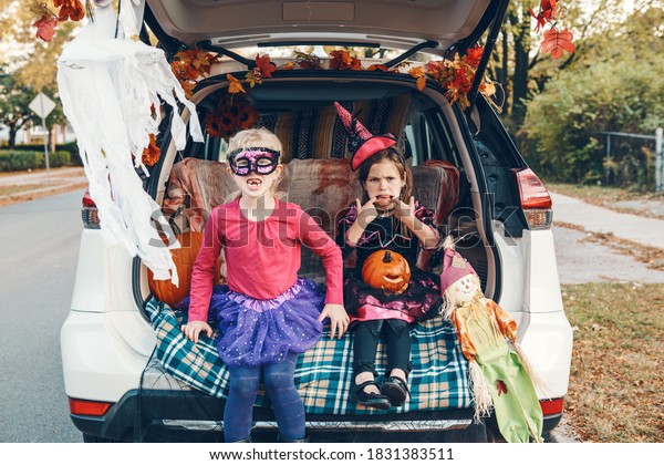 Trick\
or trunk. Children siblings sisters celebrating Halloween in trunk\
of car. Friends kids girls preparing for October holiday outdoor.\
Social distance and safe alternative\
celebration.
