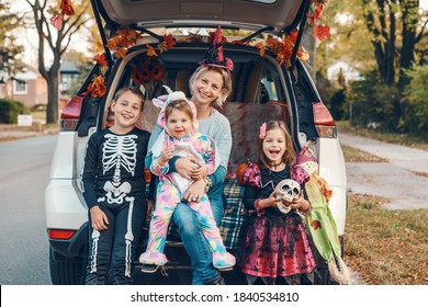 Trick Or Trunk. Family Celebrating Halloween In Trunk Of Car. Mother With Three Children Kids Celebrating Traditional October Holiday Outdoor. Social Distance And Safe Alternative Celebration.